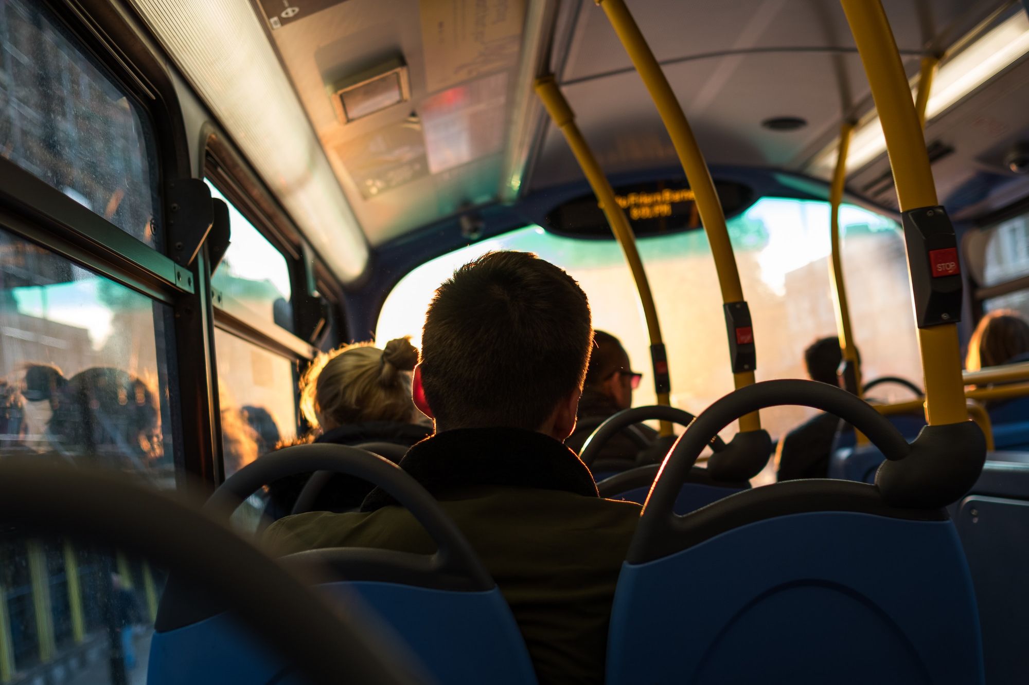 Imagen de unas personas sentadas en un autobús tomada desde atras. Photo by Mediocre Studio on Unsplash